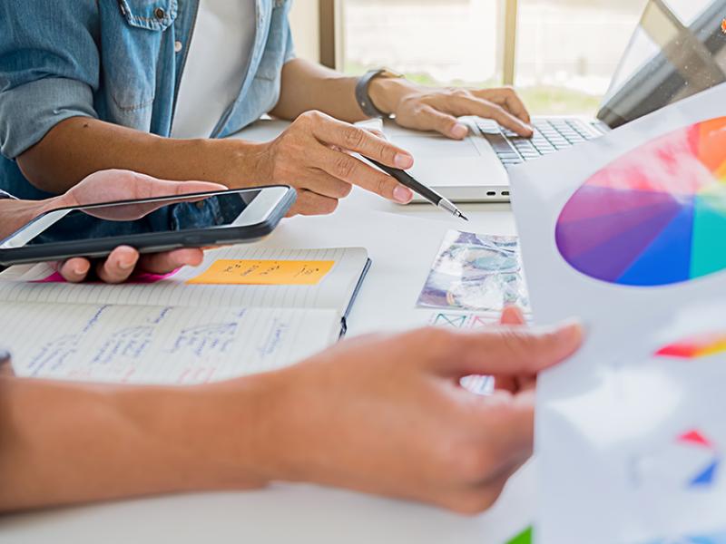 two people at a desk looking at notes and a color wheel